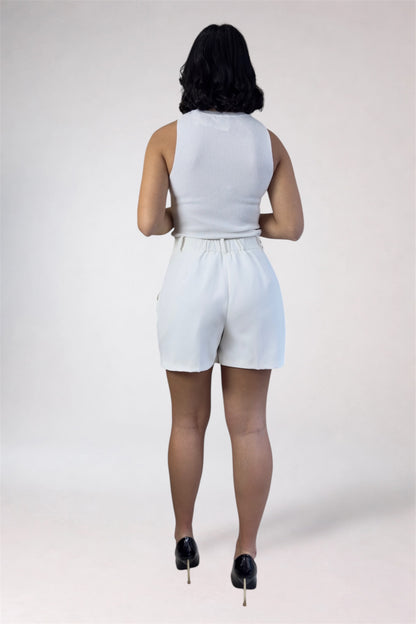 Person wearing a white sleeveless top and shorts on a plain background