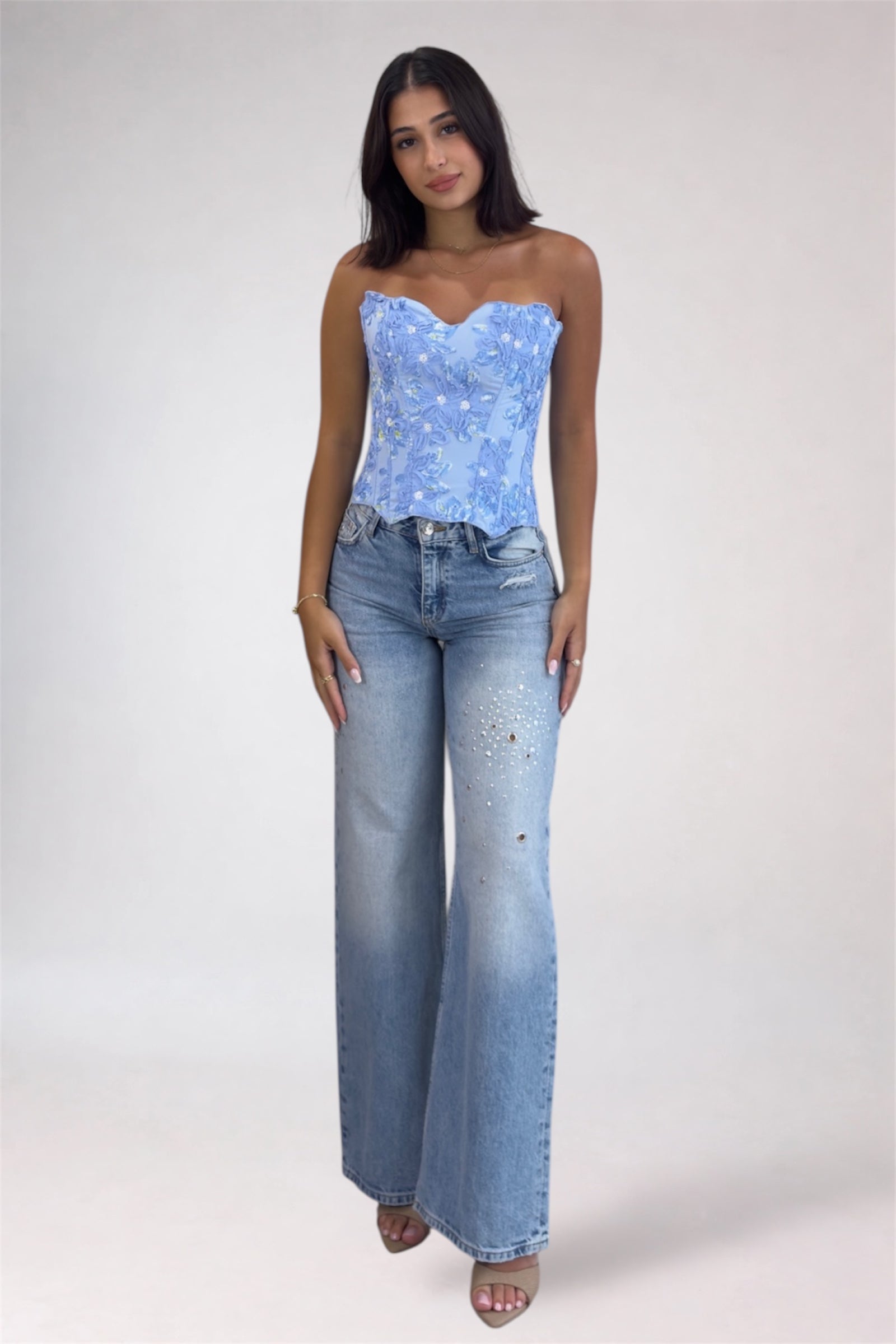 Woman wearing a blue strapless top and jeans on a white background