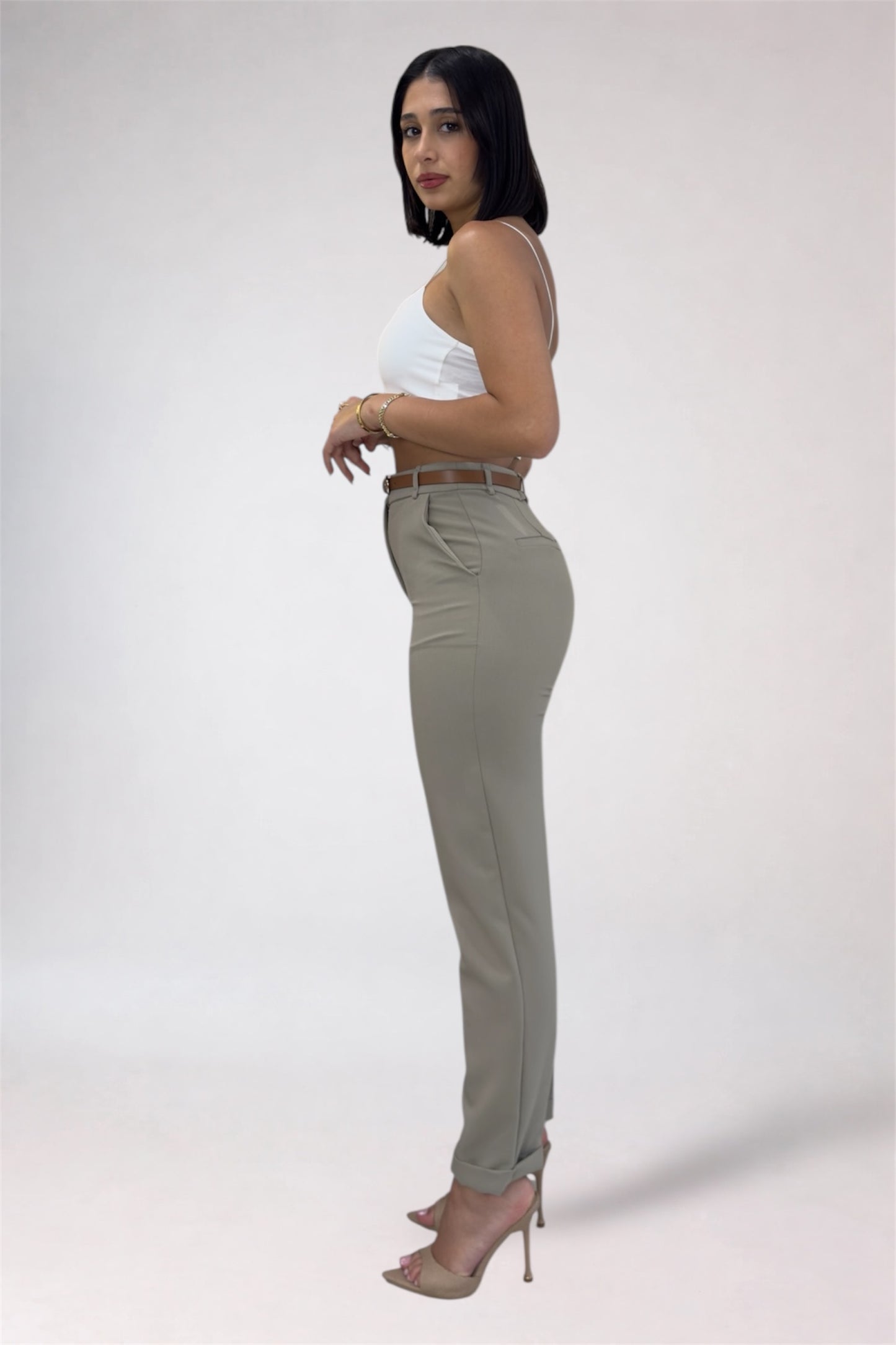 Woman wearing a white top and beige pants on a plain background