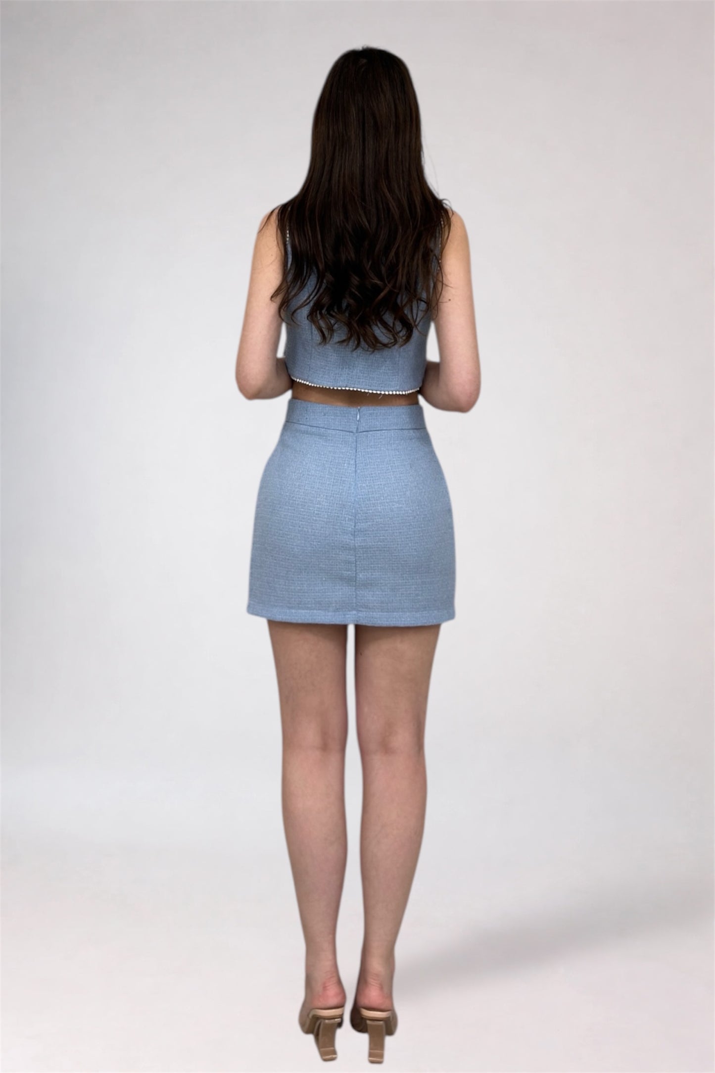 Woman wearing a light blue two-piece outfit on a white background