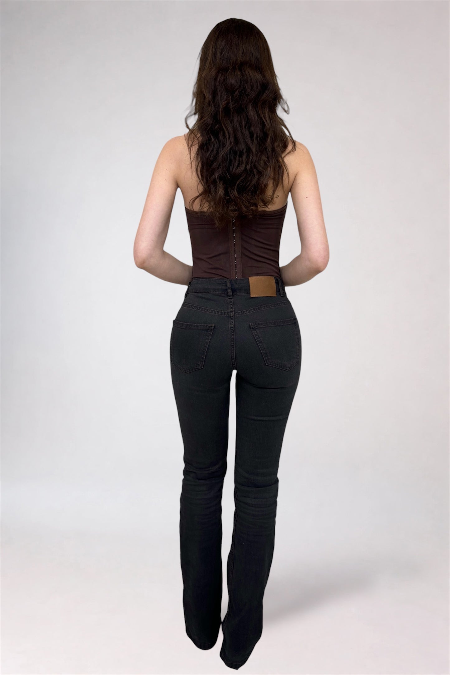 Woman wearing a brown top and black pants on a white background