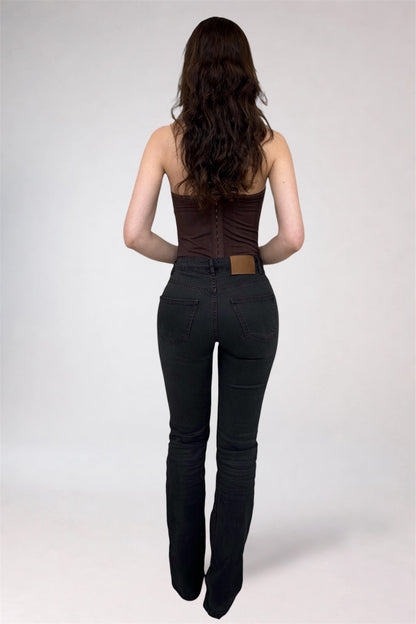 Woman wearing a brown top and black pants on a white background
