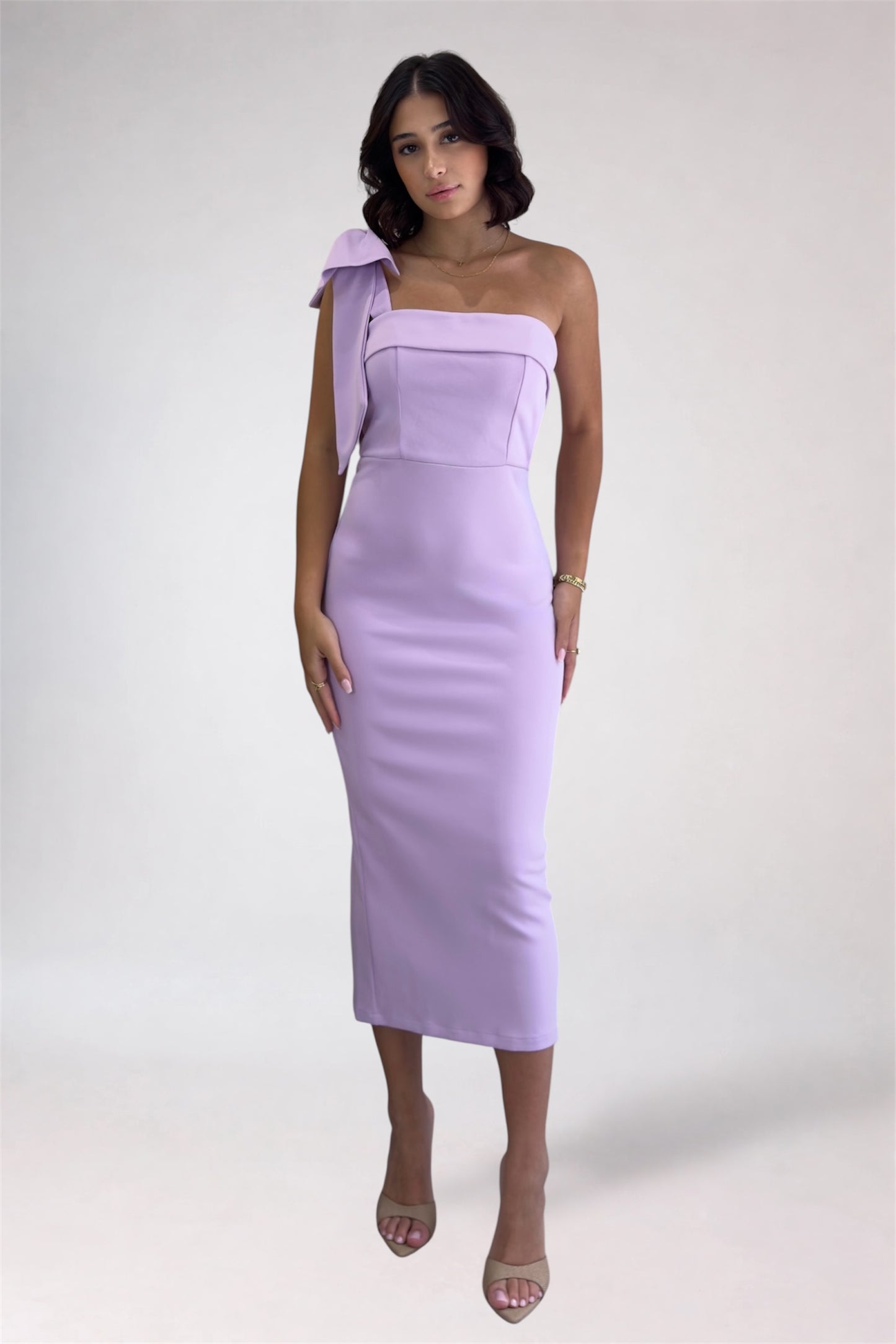 Woman wearing a one-shoulder lavender dress on a white background