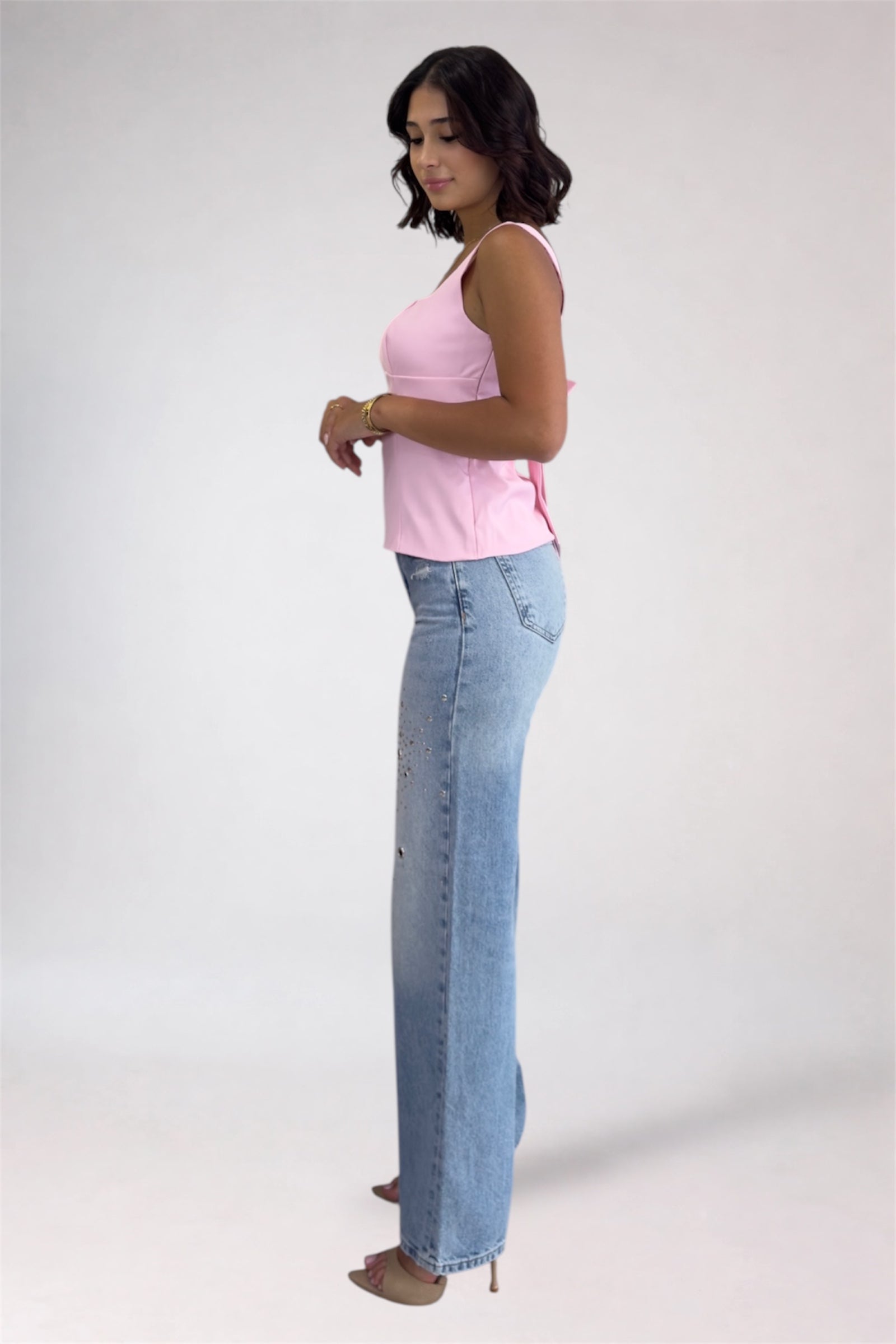 Woman wearing a pink top and blue jeans on a white background