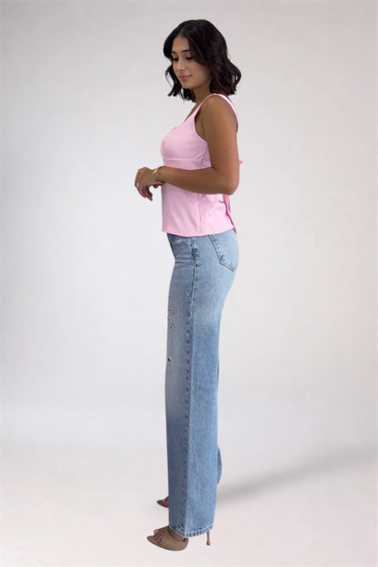 Woman wearing a pink top and blue jeans on a white background