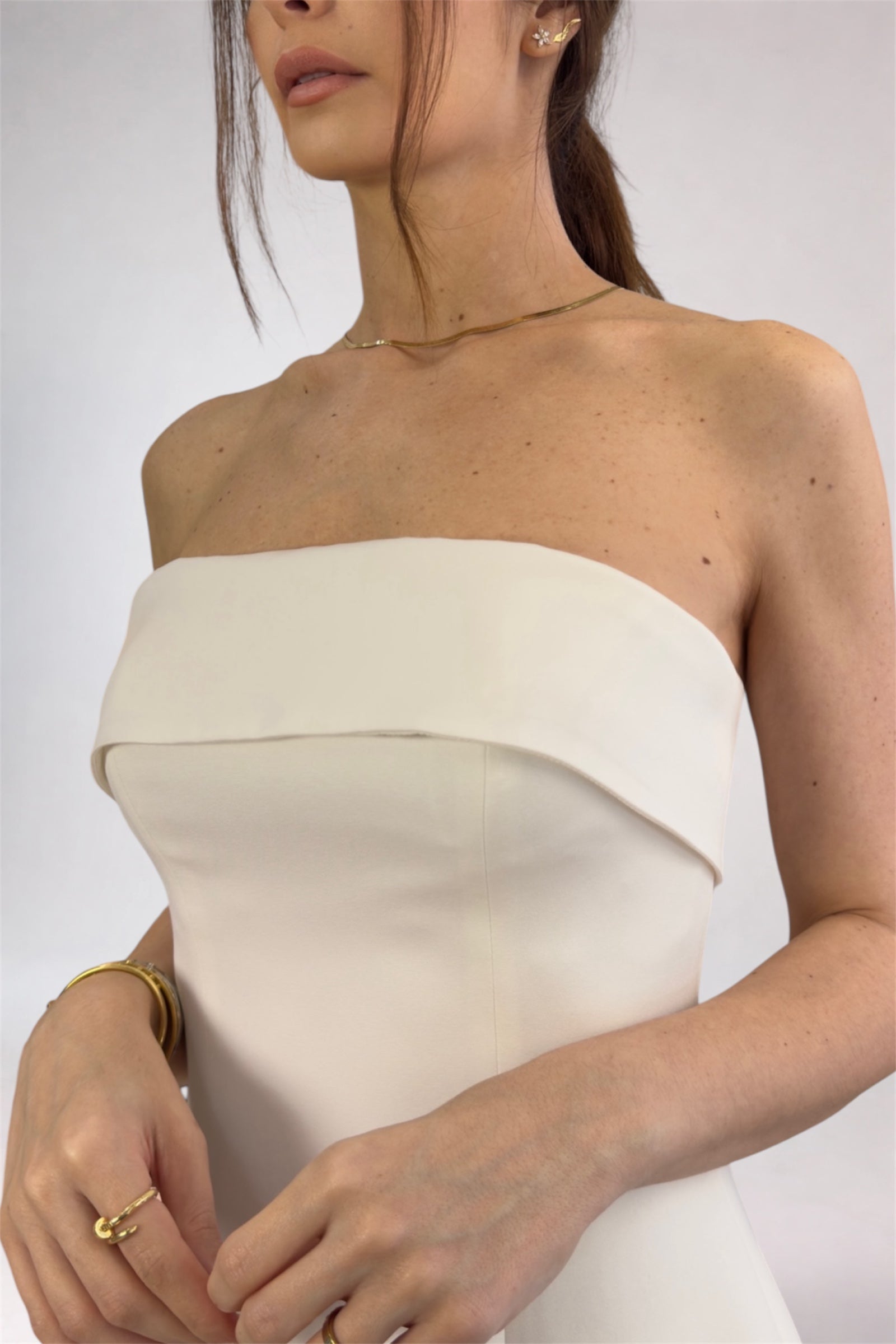 Woman wearing a strapless white dress with a plain background