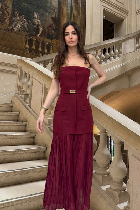 Woman in a burgundy dress standing on a staircase in an elegant interior setting