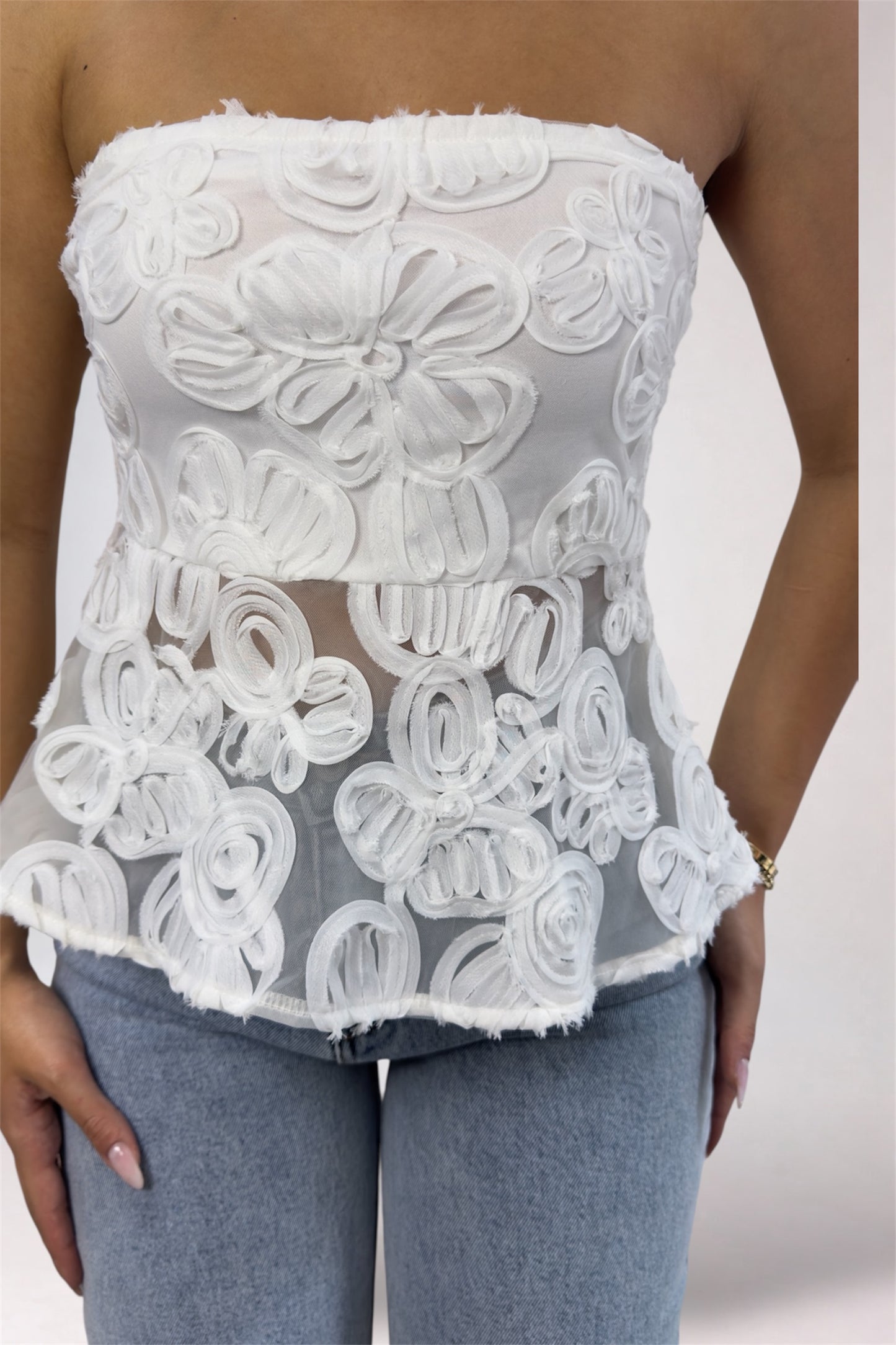 White lace strapless top worn by a person against a neutral background