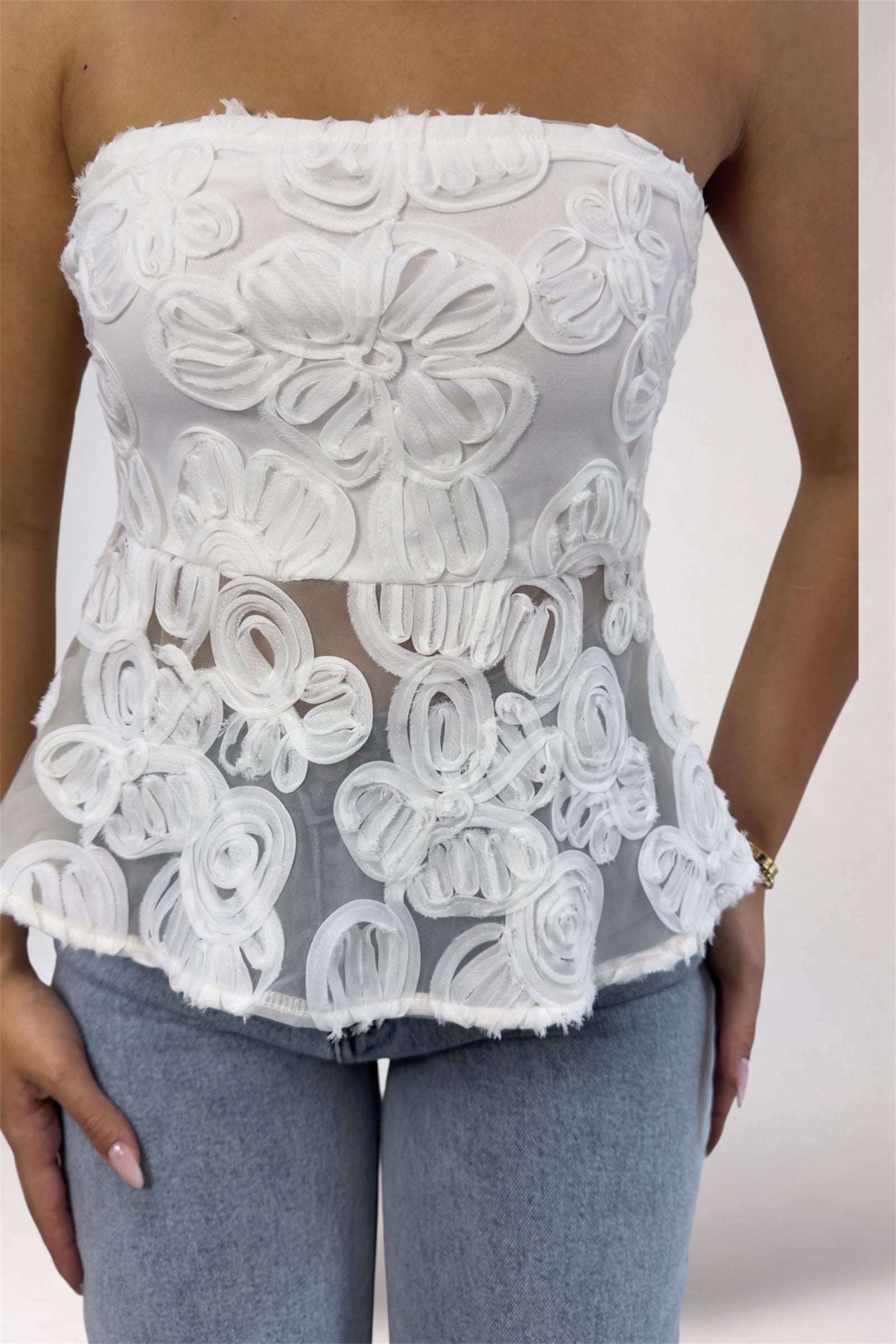 White lace strapless top worn by a person against a neutral background