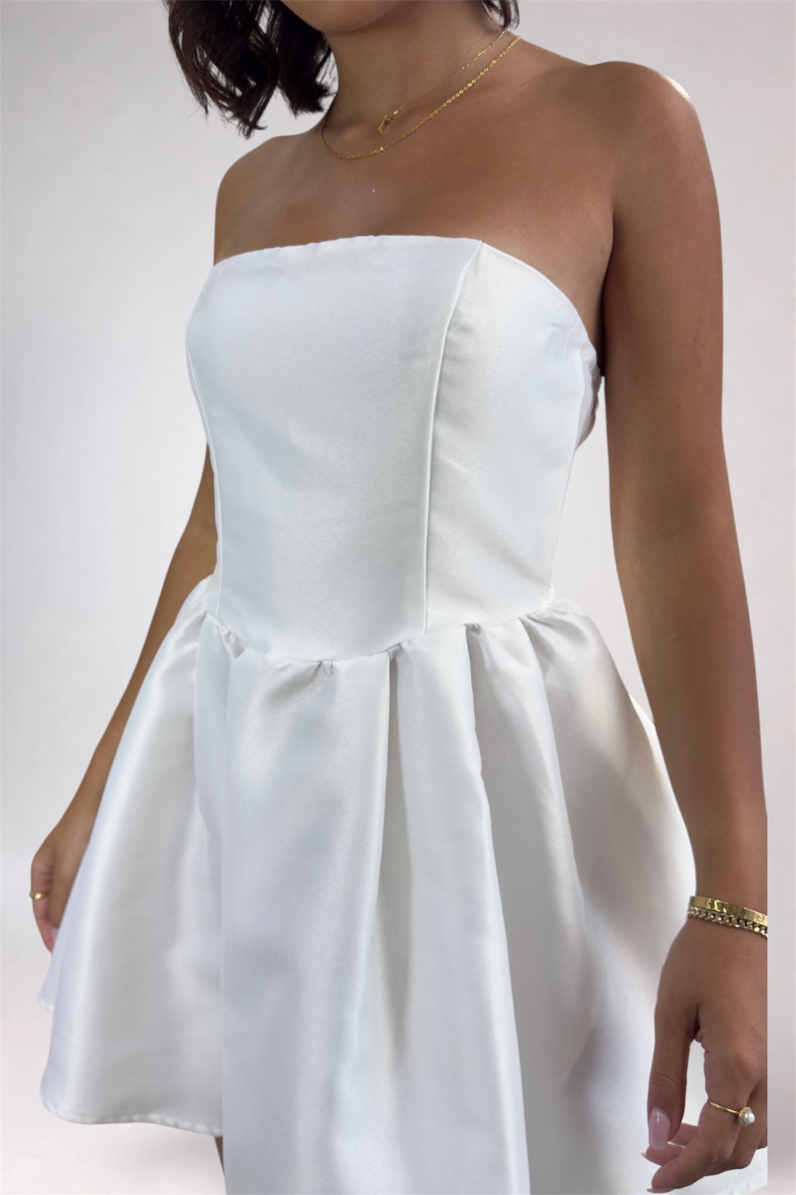 White strapless dress worn by a person on a plain background