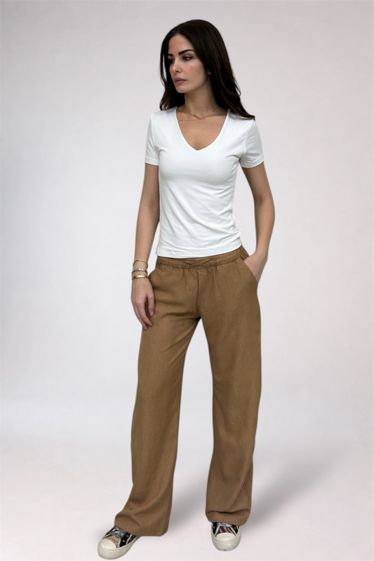 Woman wearing a white t-shirt and tan pants on a plain background