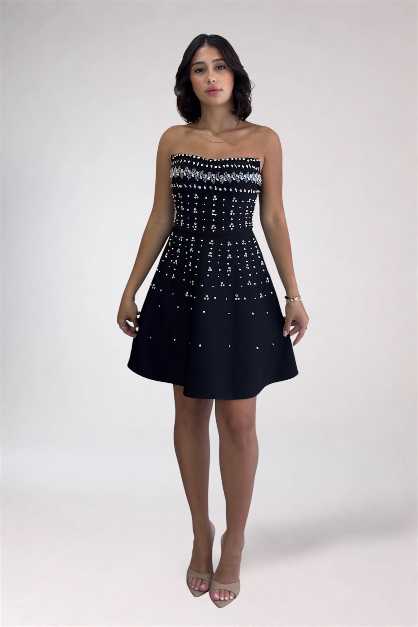 Woman wearing a strapless black dress with white pattern on a white background