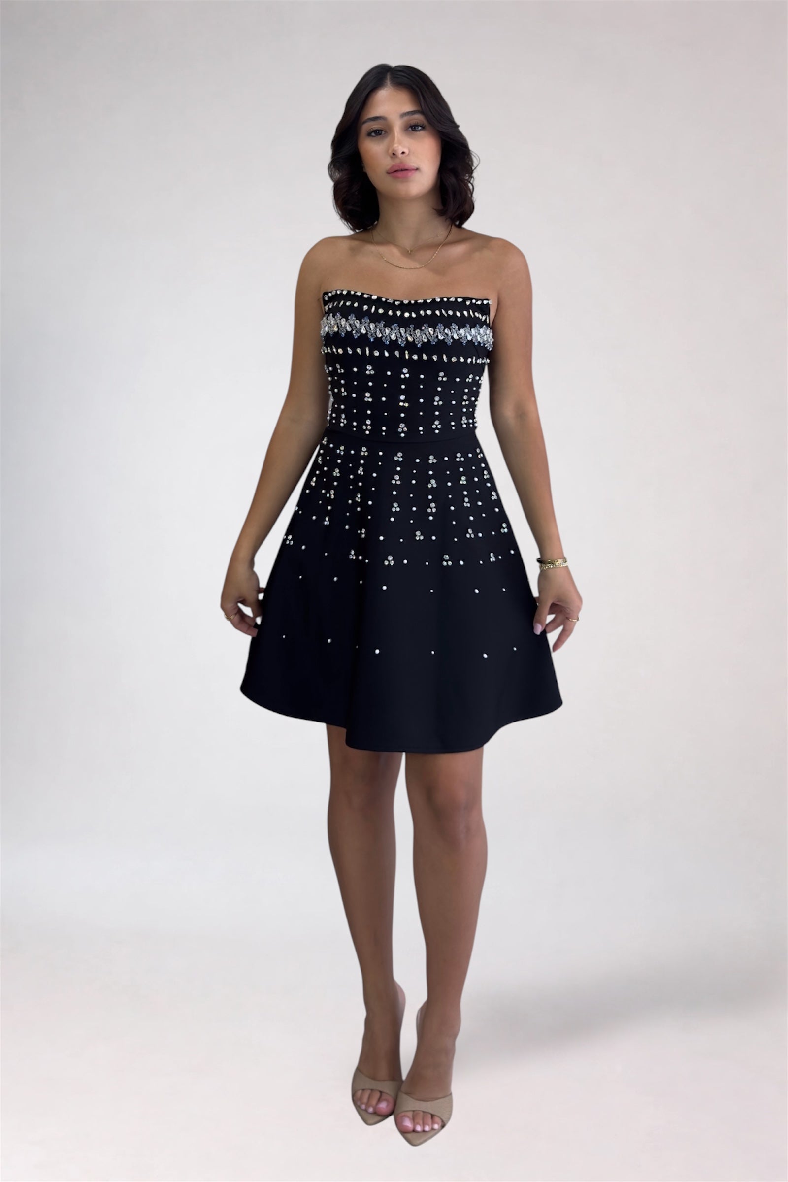 Woman wearing a strapless black dress with white pattern on a white background