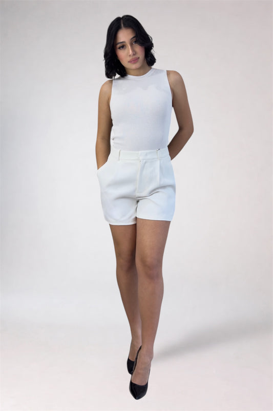 Woman wearing a white sleeveless top and shorts on a plain background