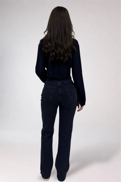 Person wearing a black outfit with flared jeans on a white background