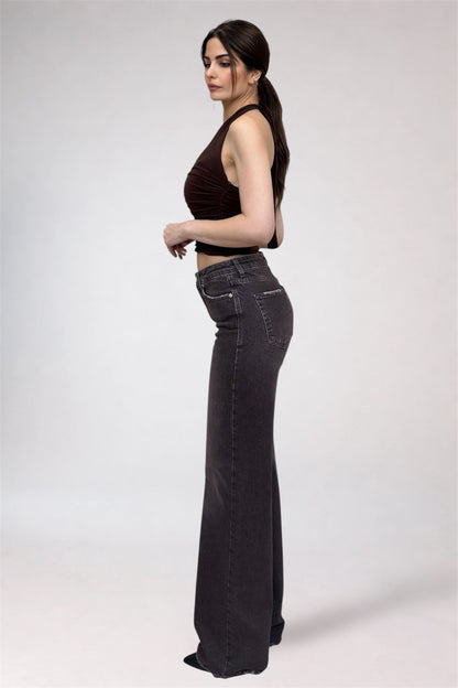 Woman wearing black high-waisted jeans and a brown top on a white background