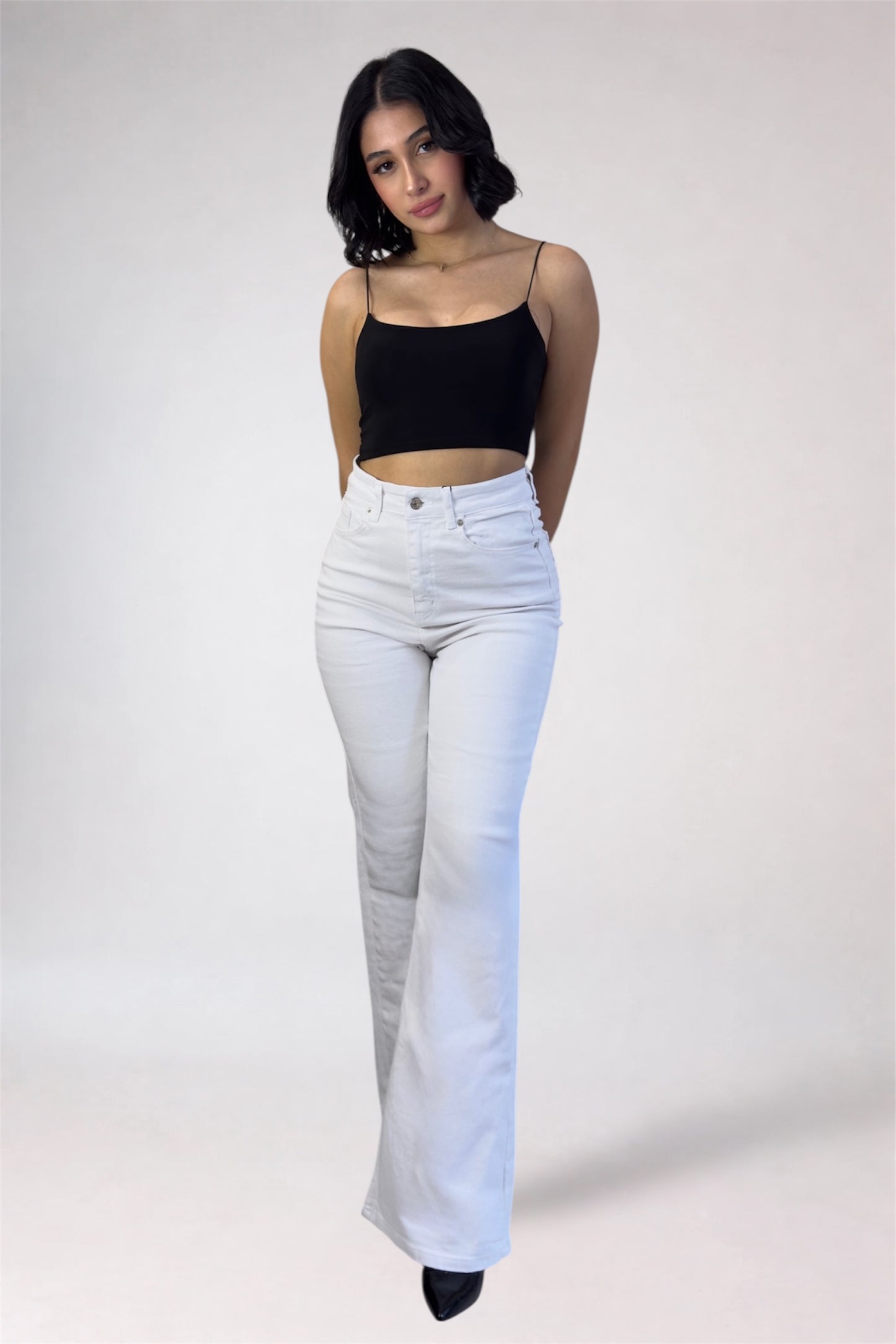 Woman wearing a black top and light blue jeans on a white background