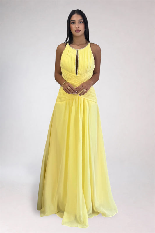 A woman modeling a sleeveless, floor-length yellow gown with a gathered halter-style bodice and flowing skirt, photographed against a plain light gray studio background.