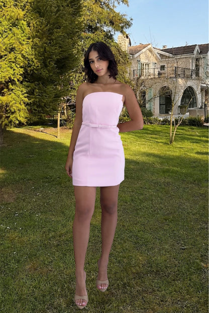Woman in a pink dress standing in a garden with a house in the background