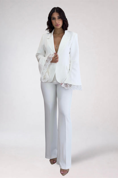 Woman wearing a white outfit with lace details on a plain background