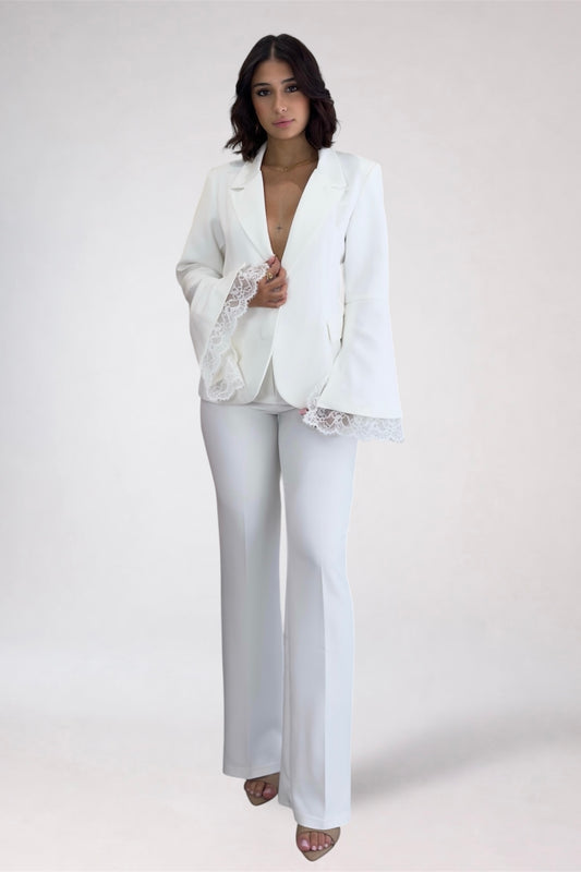 Woman wearing a white outfit with lace details on a plain background