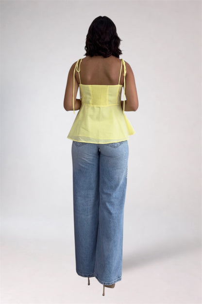 Woman wearing a yellow top and blue jeans on a white background