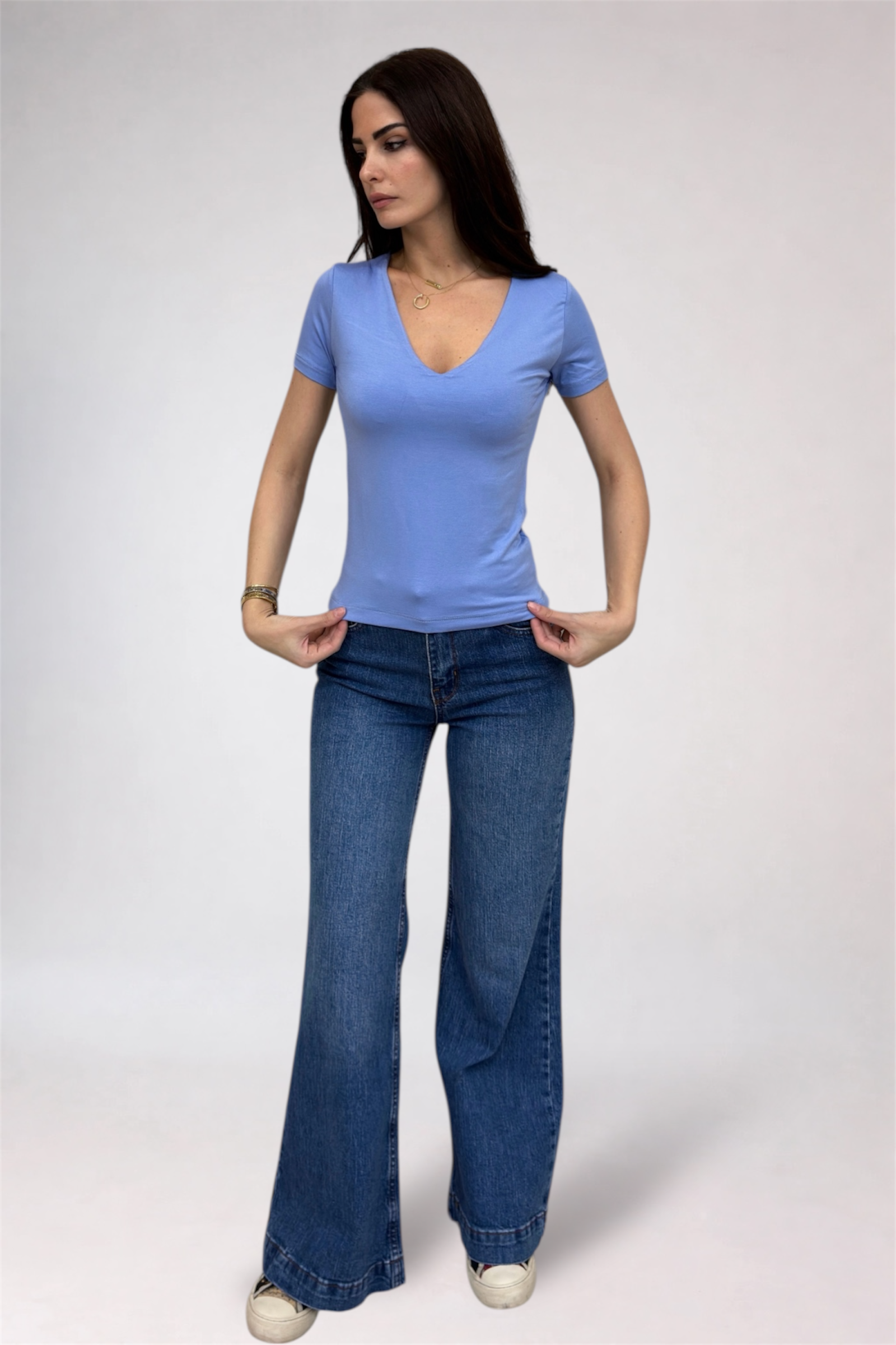 Woman wearing a blue t-shirt and jeans on a plain background