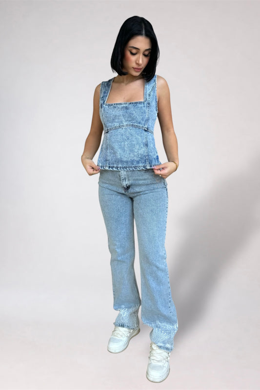 Woman wearing light blue denim overalls on a plain background