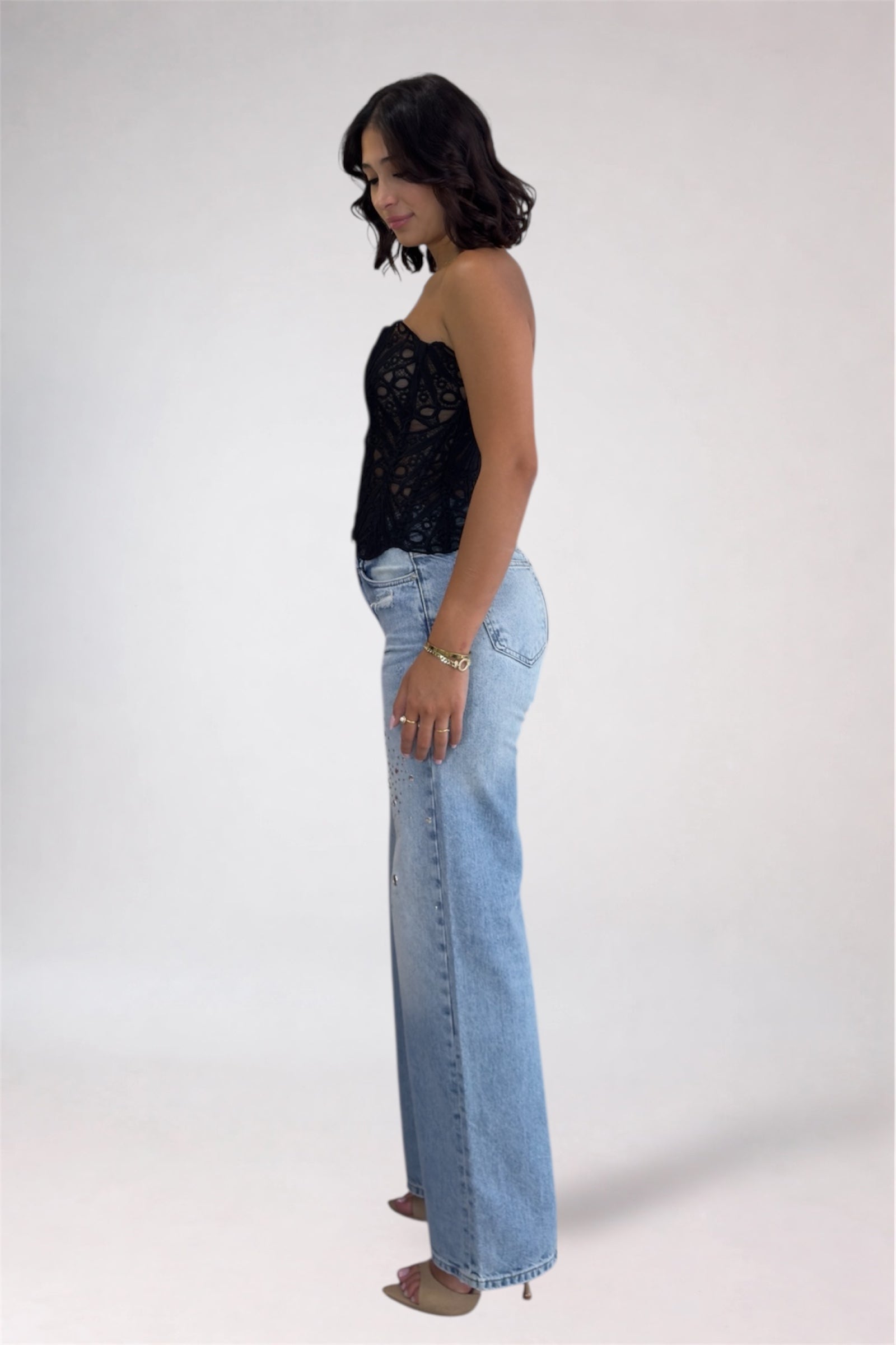Woman wearing a black top and light blue jeans on a white background