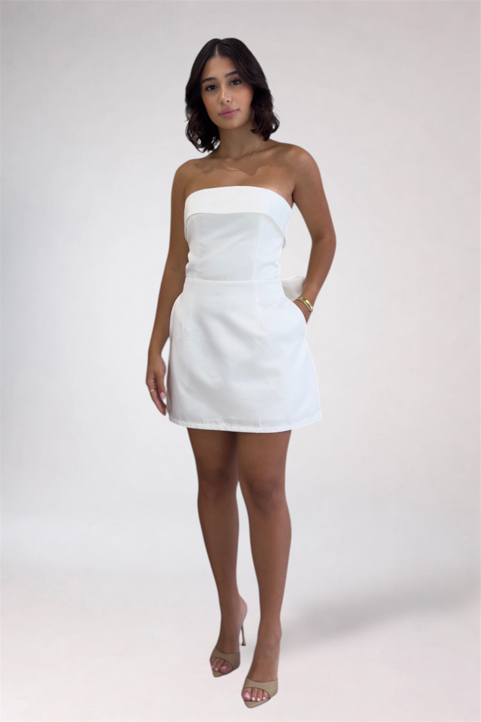 Woman wearing a white strapless dress against a plain background