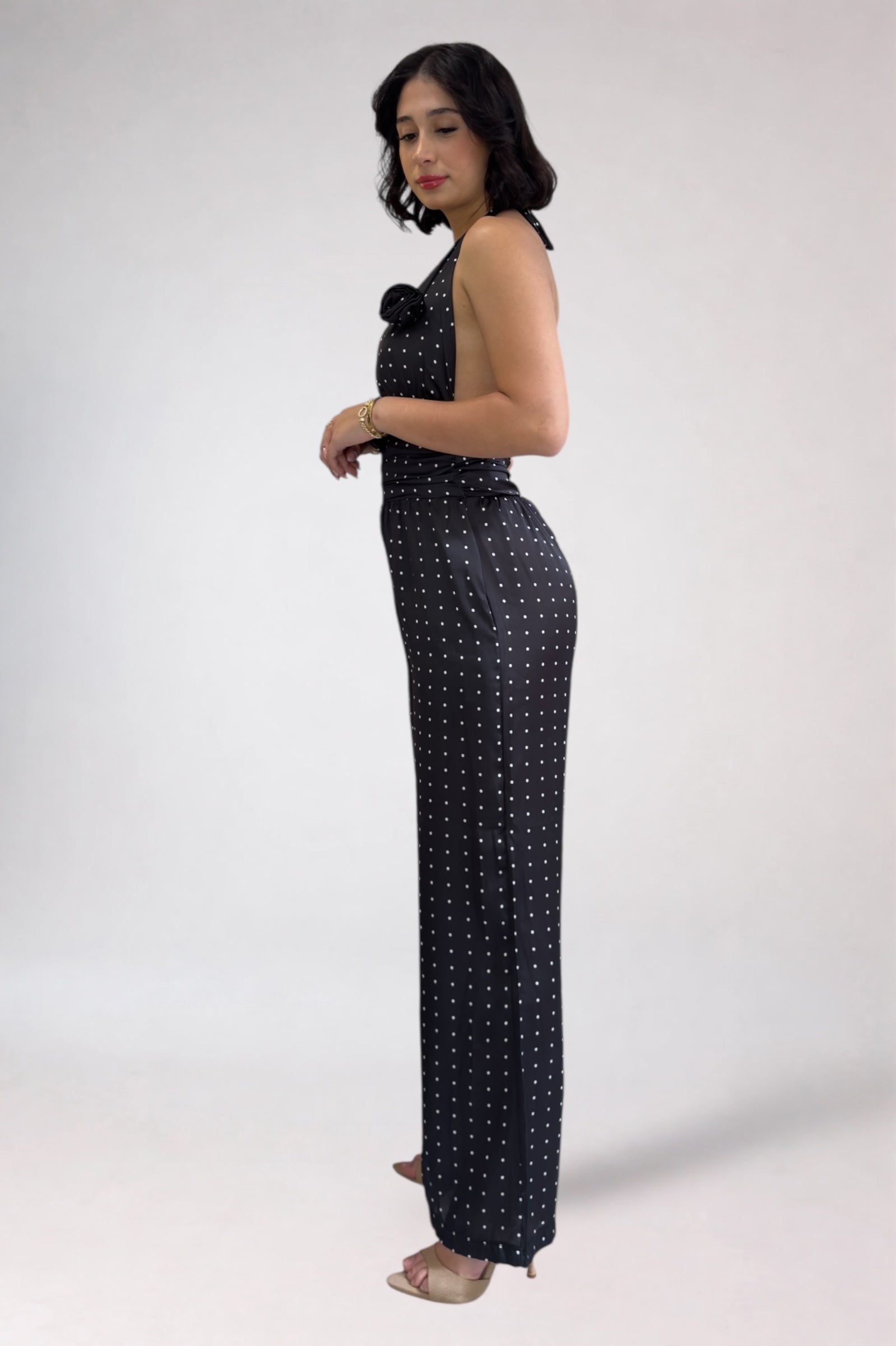 Woman wearing a black polka dot jumpsuit on a white background