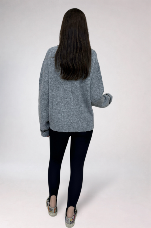 Person wearing a gray sweater and black pants on a white background