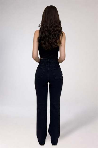 Person wearing black high-waisted jeans and a black top on a white background