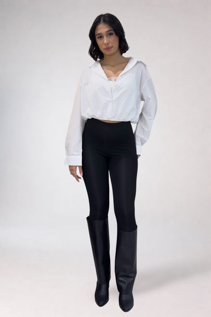 Person wearing a white blouse, black pants, and black boots on a white background