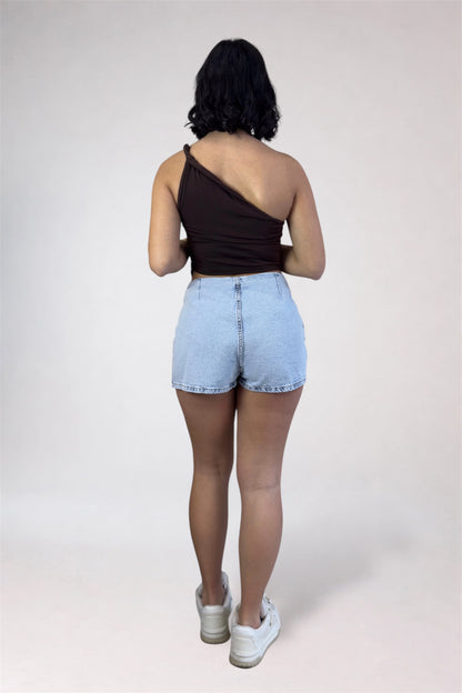 Person wearing a black top and light blue denim shorts on a white background
