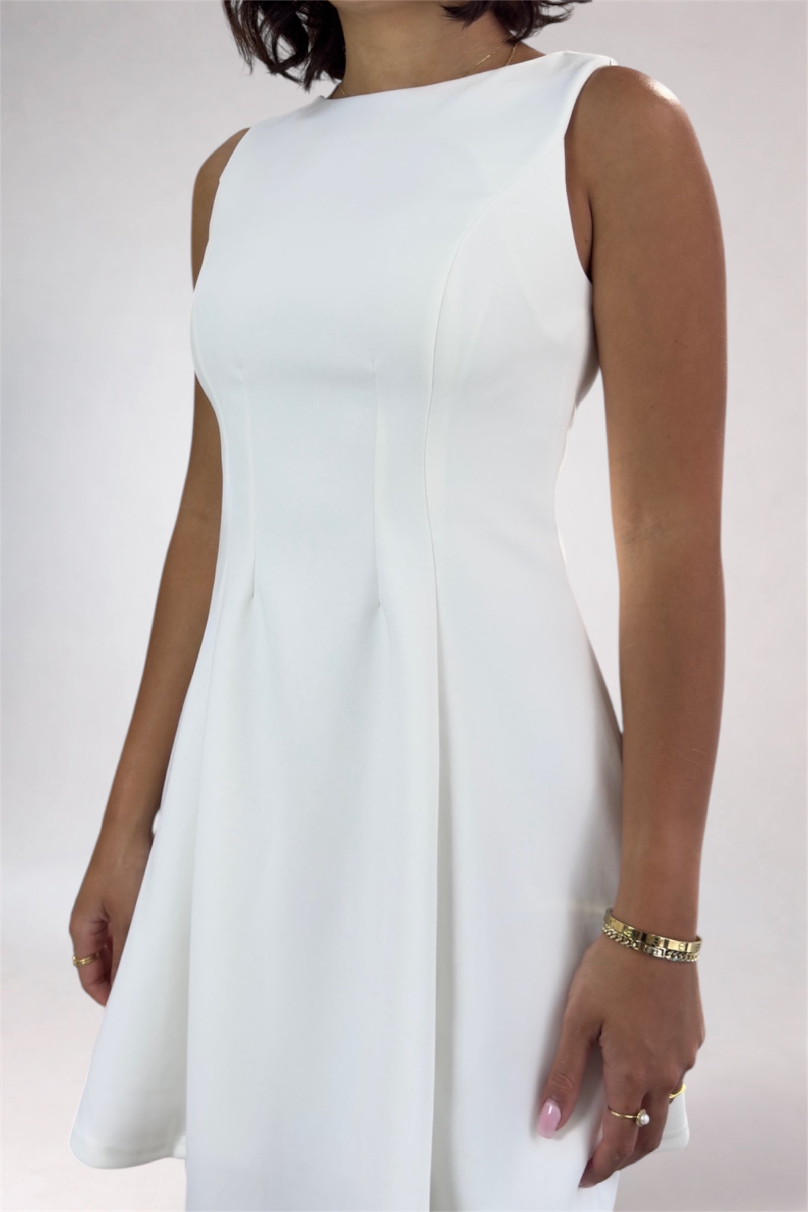 White sleeveless dress worn by a person on a plain background