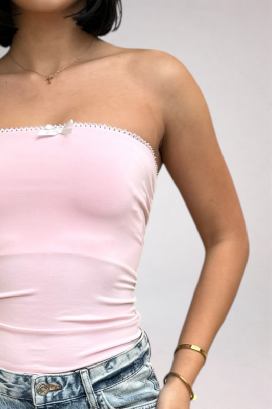 Person wearing a light pink strapless top and denim shorts on a plain background