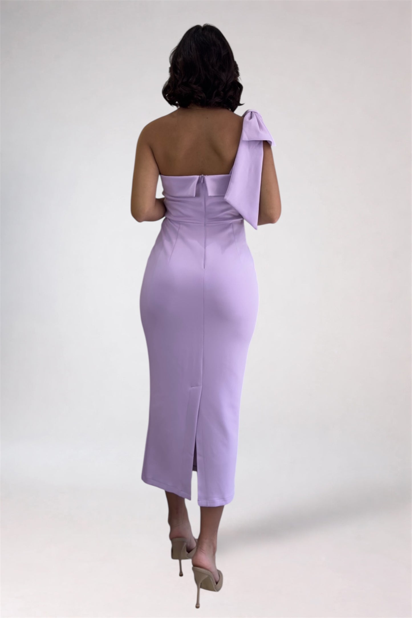 Woman wearing a lavender one-shoulder dress with a white background
