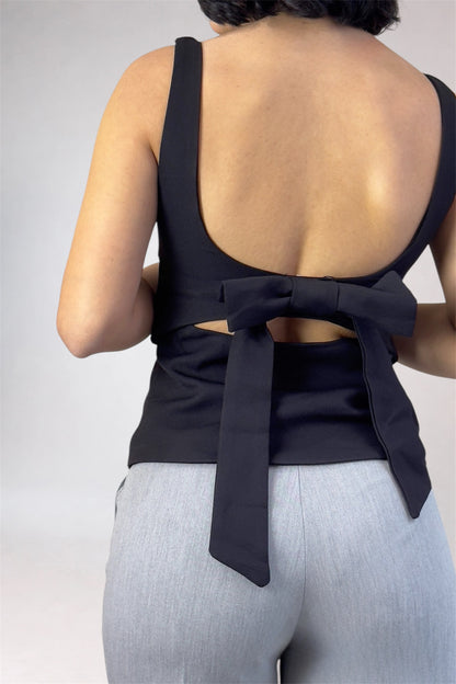 Black open-back top with a bow detail on a plain background