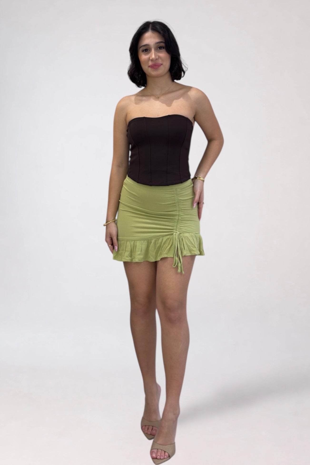 Woman wearing a black top and green skirt on a white background