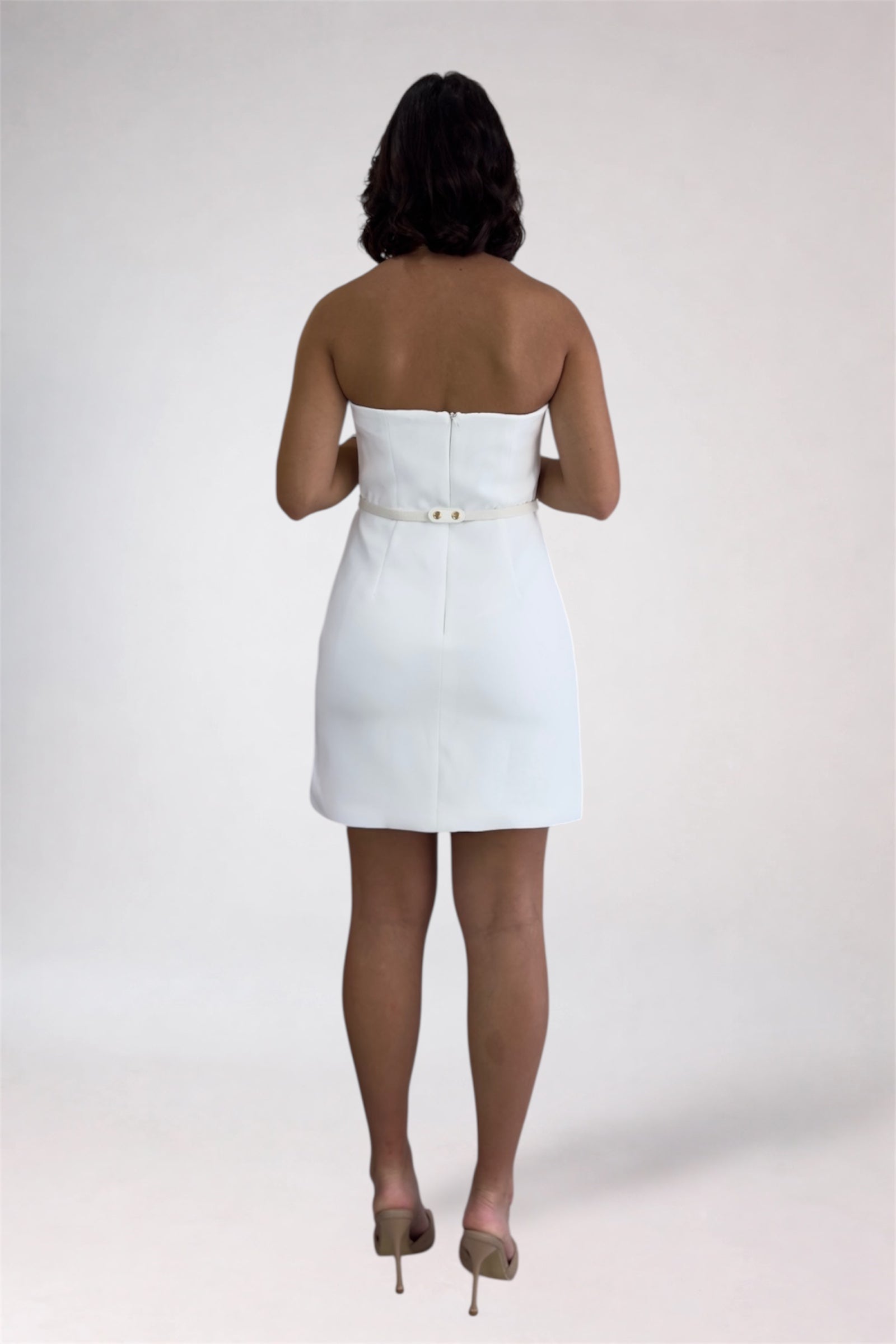 Person wearing a white strapless dress on a plain background