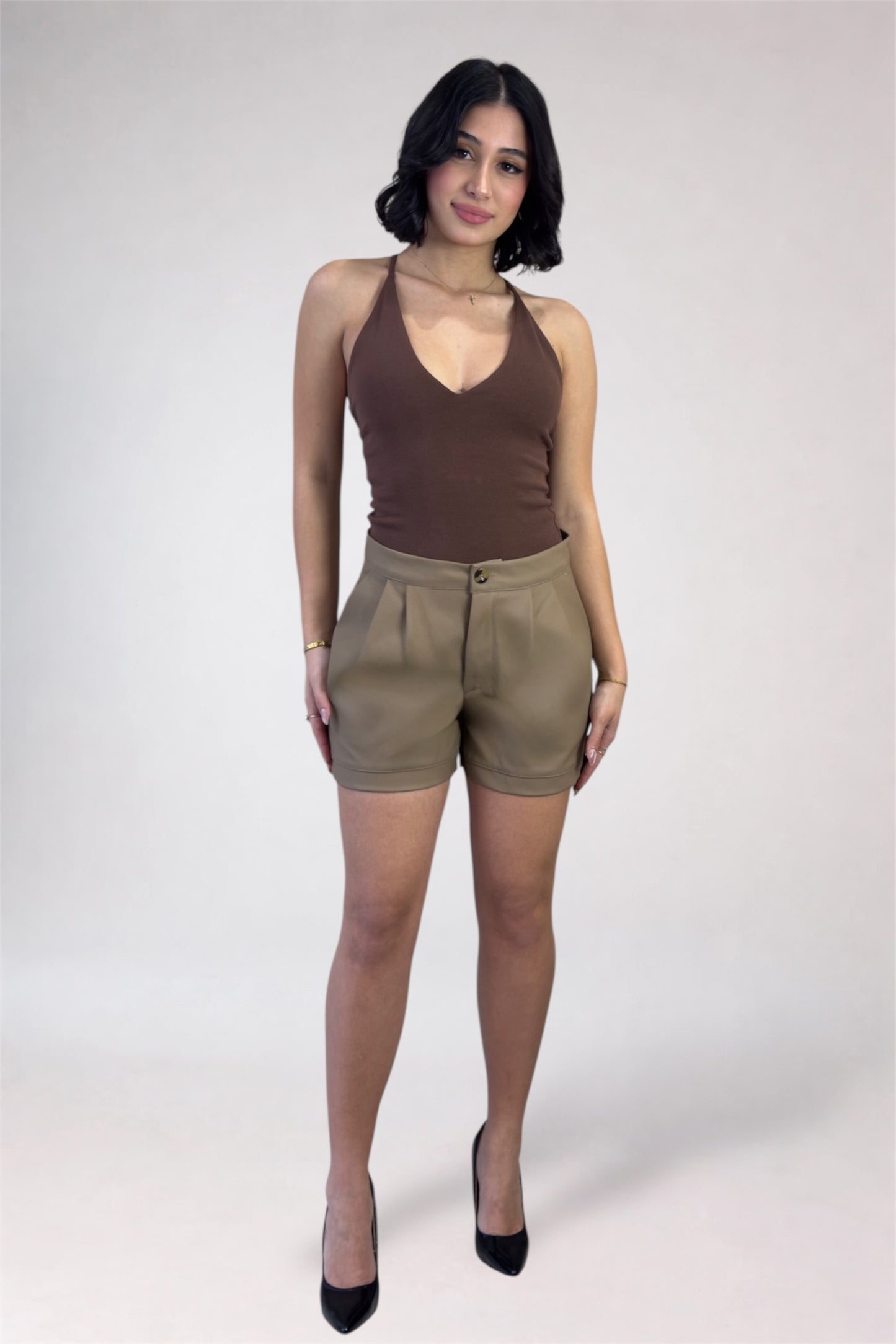 Woman wearing a brown tank top and beige shorts on a white background