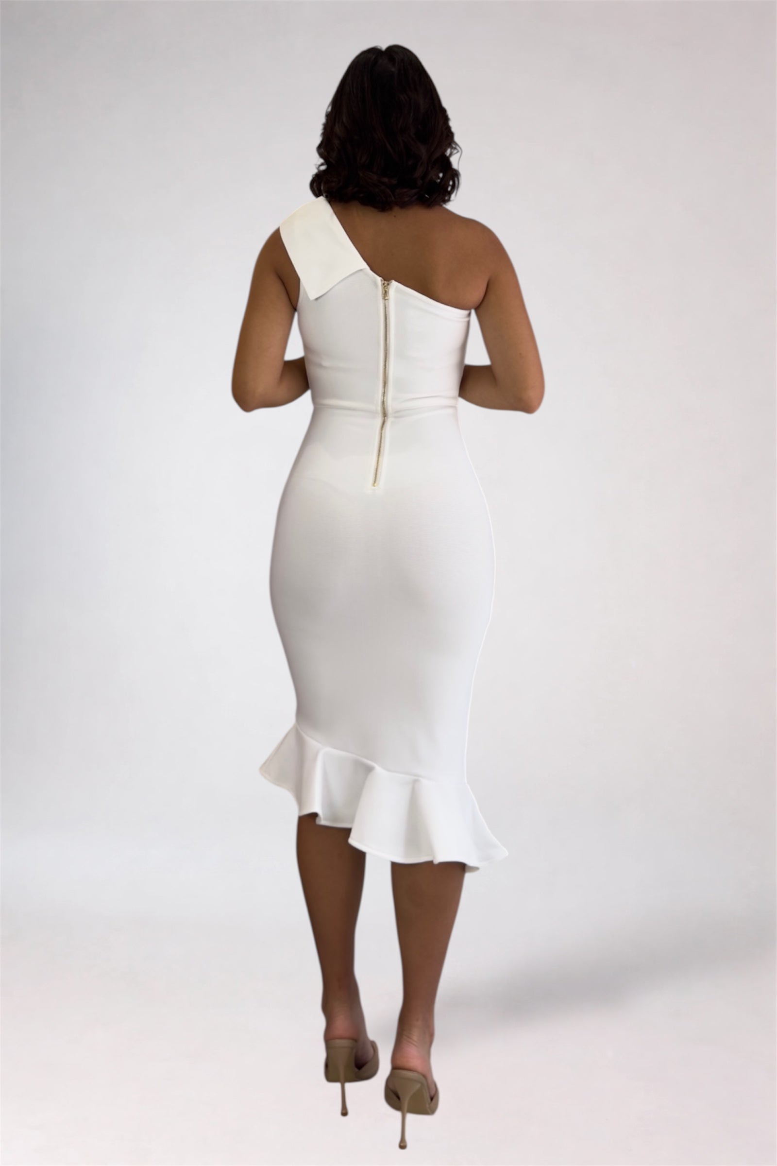 Woman wearing a white one-shoulder dress on a plain background