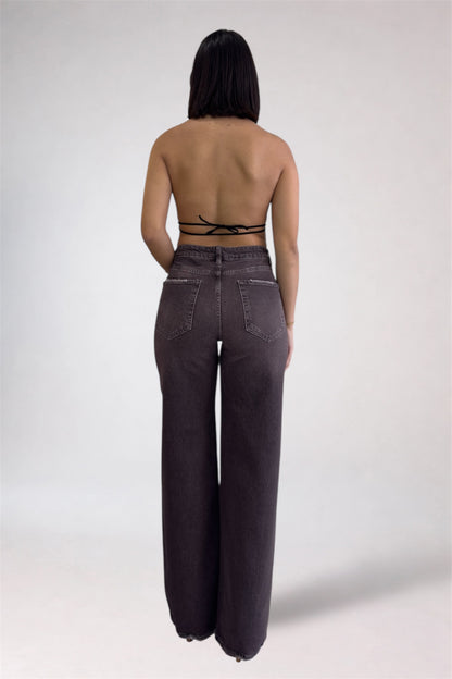 Person wearing high-waisted dark jeans on a plain background