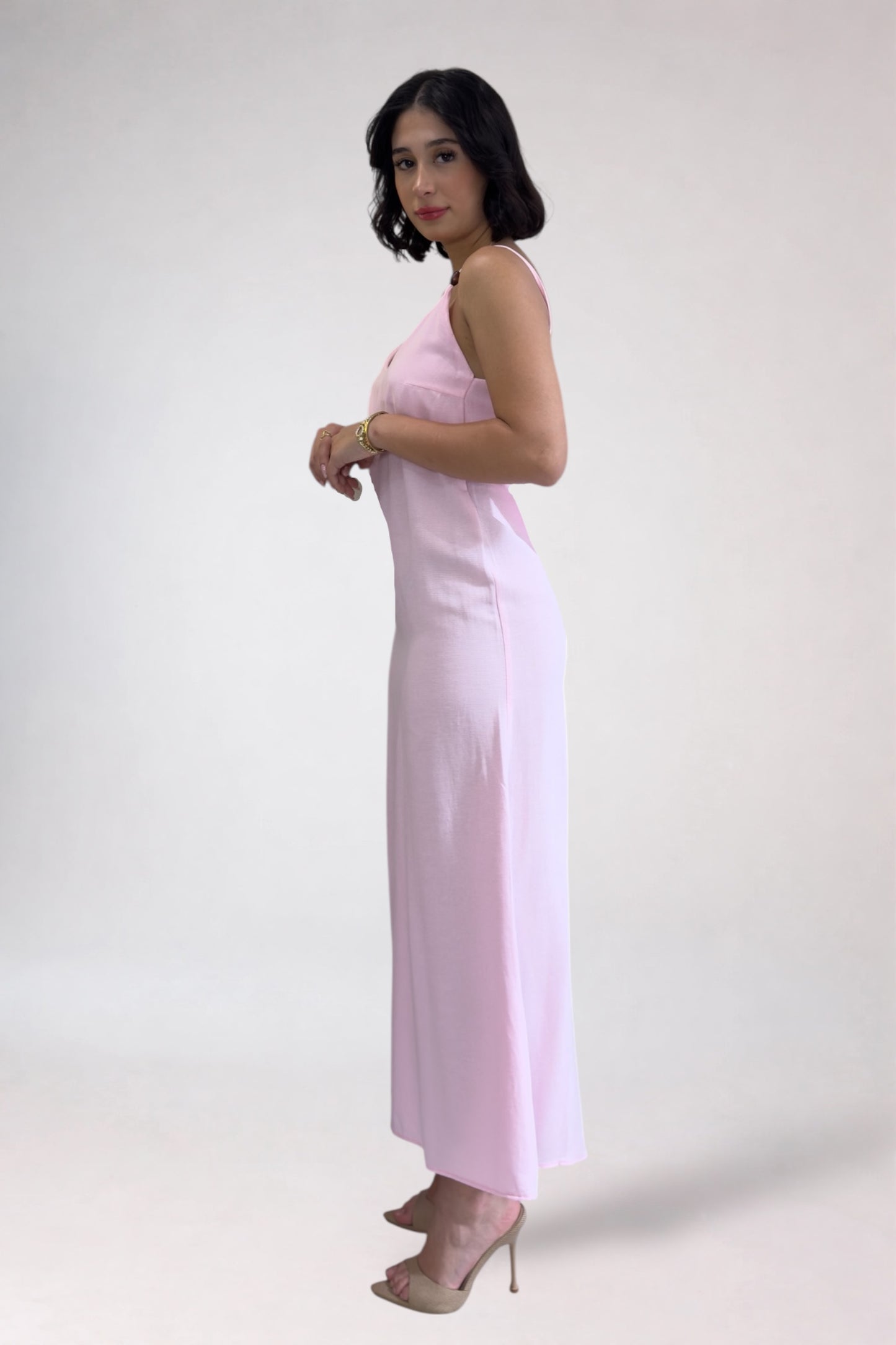 Woman wearing a light pink sleeveless top and high-waisted pants on a white background