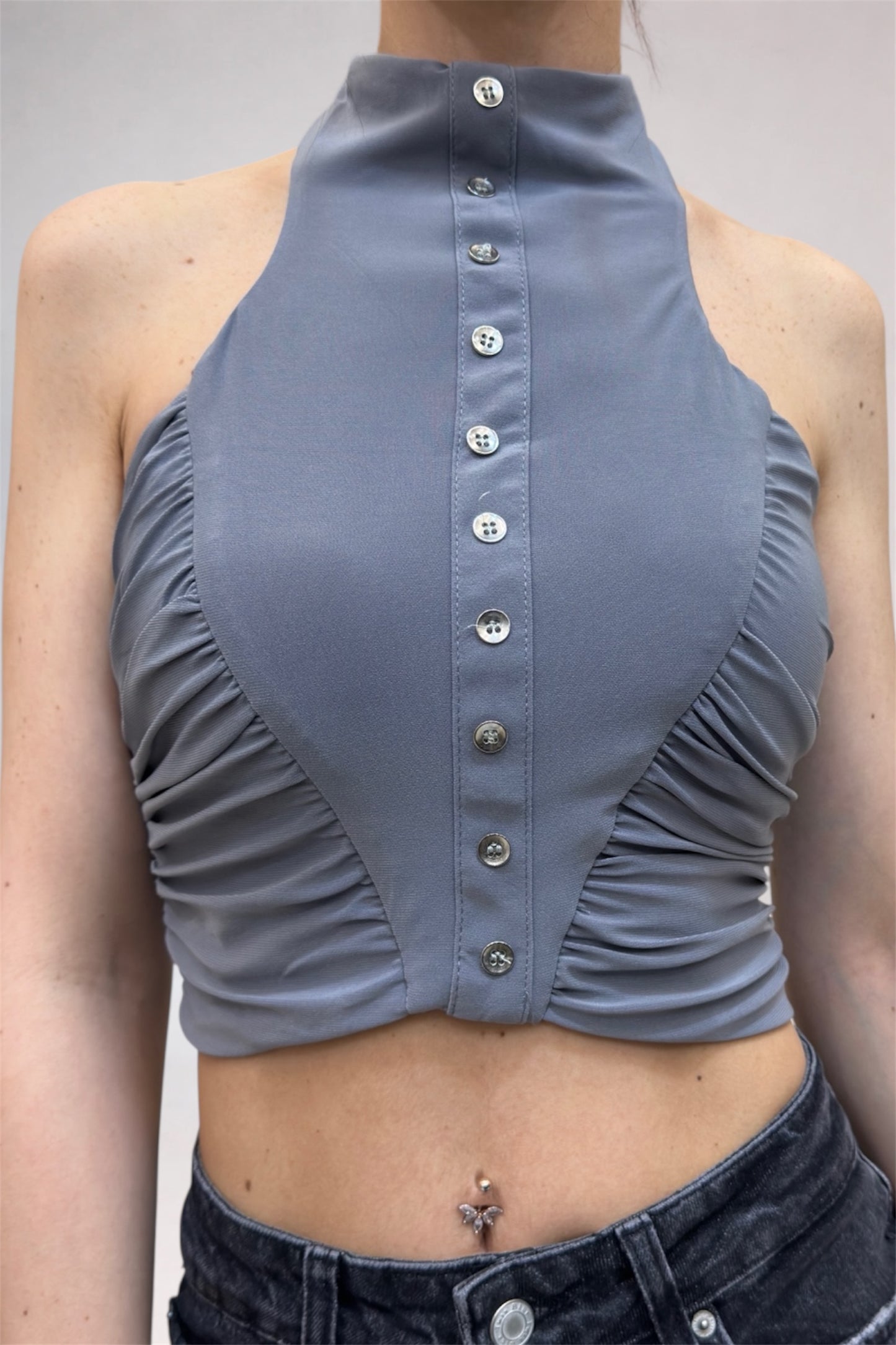 Gray halter top with button details worn by a person against a neutral background