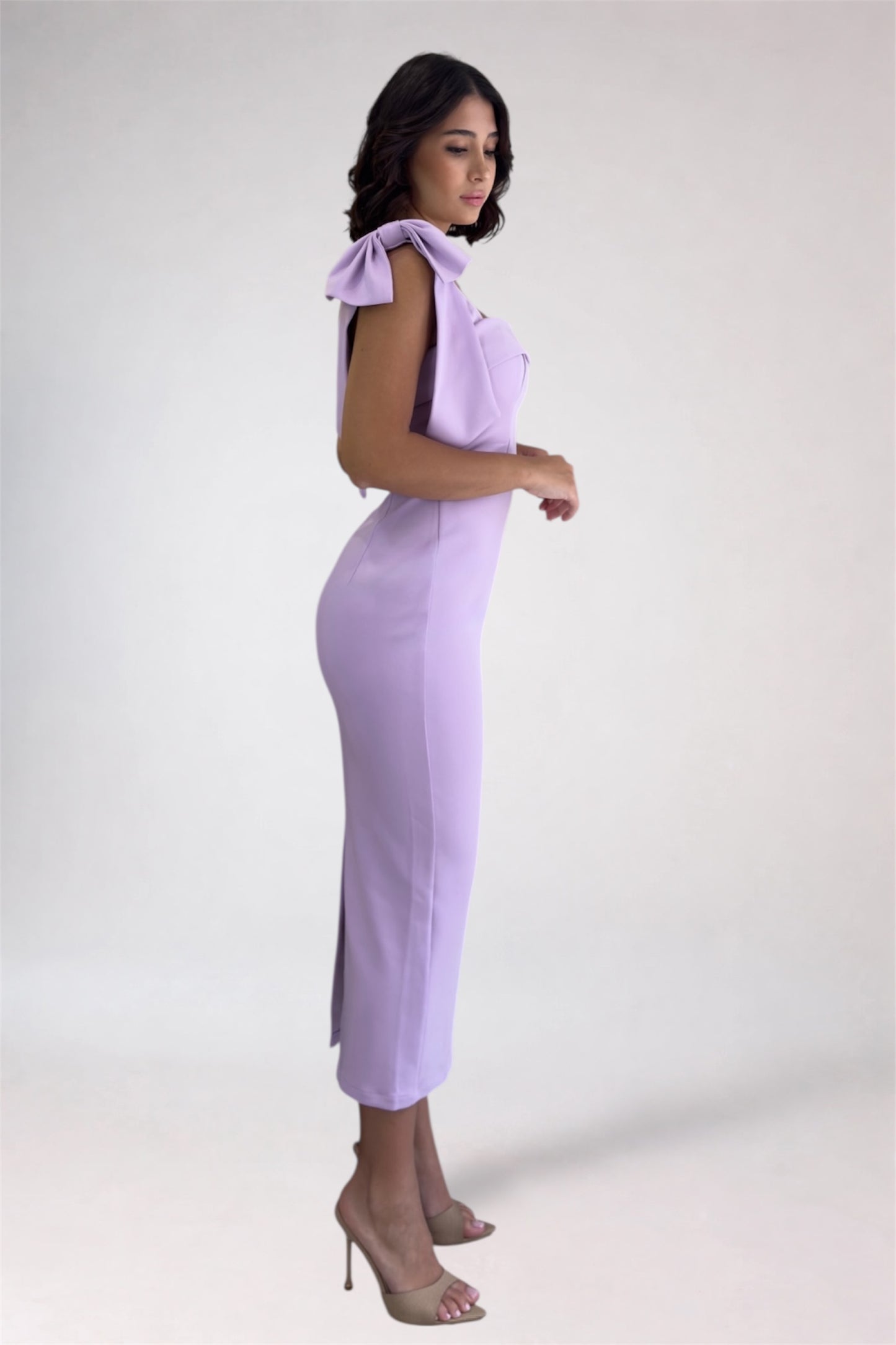 Woman wearing a light purple dress with bow shoulders on a white background