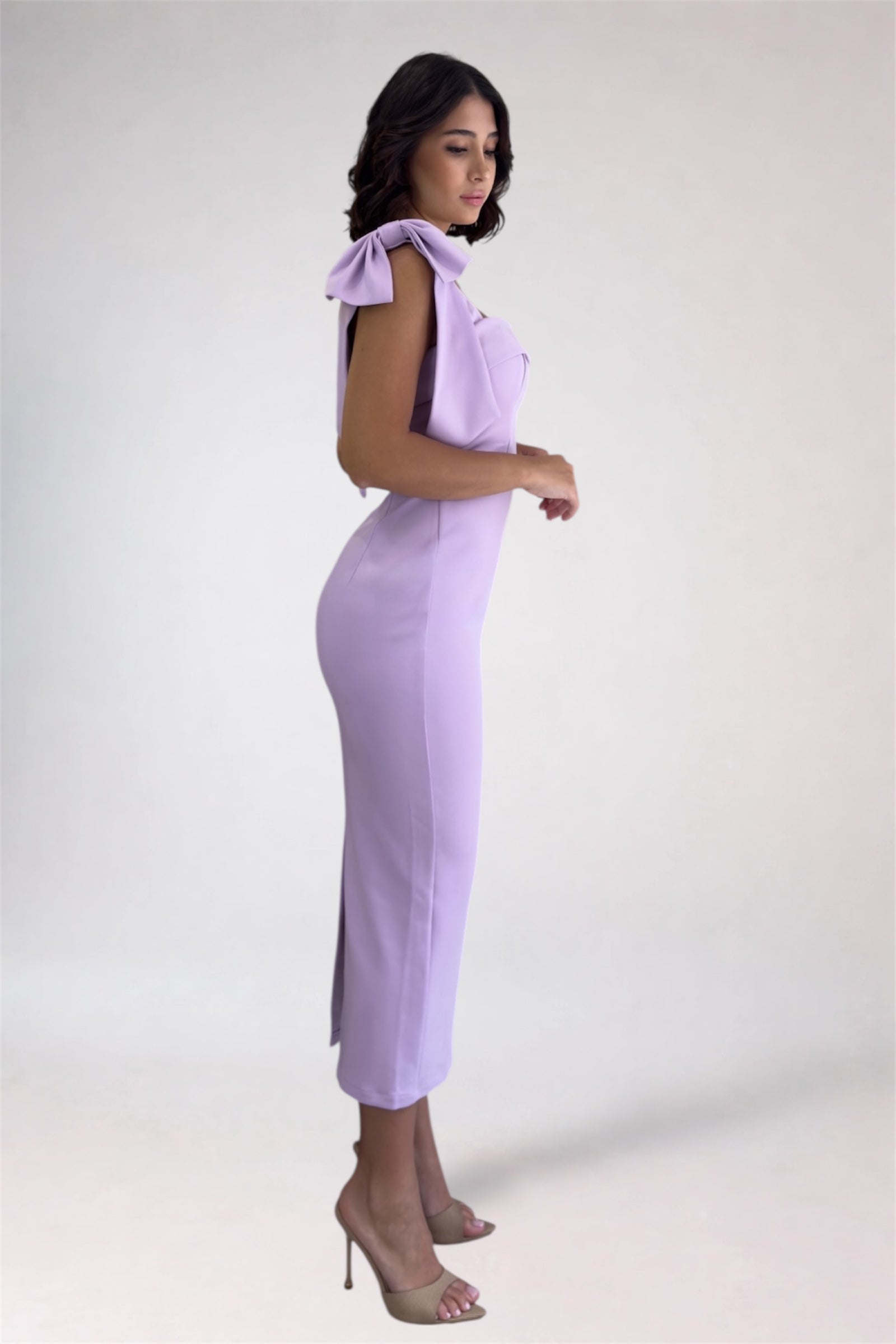 Woman wearing a light purple dress with bow shoulders on a white background