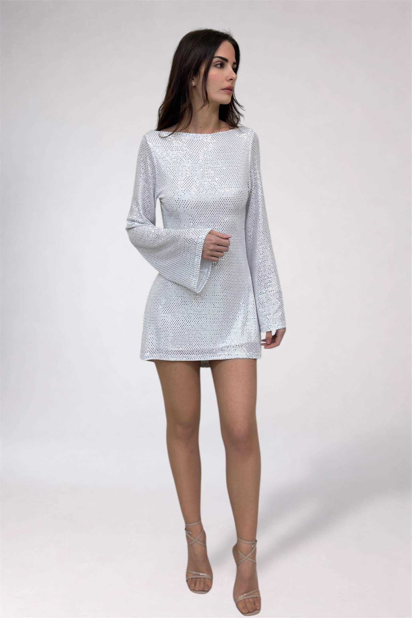 Woman wearing a light gray dress with long sleeves on a white background