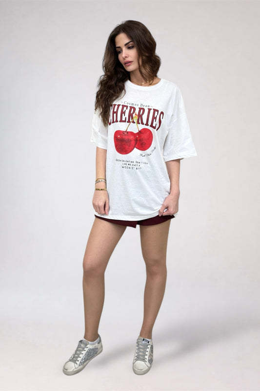 Woman wearing a white t-shirt with cherry design on a plain background
